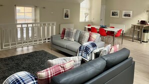 A modern living room with a grey sofa, red chairs, and a dining area with a white table. - Lovely spacious 2 bedroom, 2 bathroom Mews Cottage, Glasgow (Glasgow)