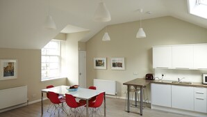 A modern kitchen with white cabinets, a wooden countertop, and a red chair at the dining table. - Lovely spacious 2 bedroom, 2 bathroom Mews Cottage, Glasgow (Glasgow)