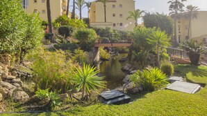 A courtyard with a small pond, palm trees, and a bridge. - Cubo's Apartamento Doña Lola / communal swimming pool / free wifi / near beach (La Cala de Mijas)