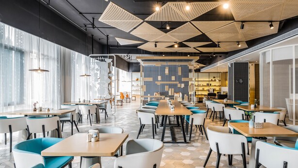 A modern dining area with hexagonal patterned flooring, wooden tables, and chairs with teal cushions. - Atour S Hotel South Gate Xian (Xi'an)