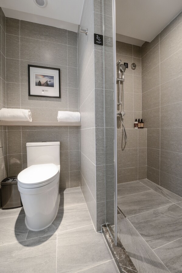 A modern bathroom with a toilet, shower, and a framed picture on the wall.