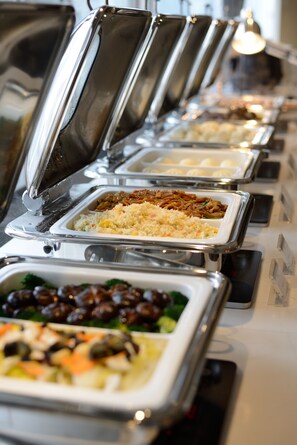 A buffet line with various food options, including rice, meat, and vegetables.