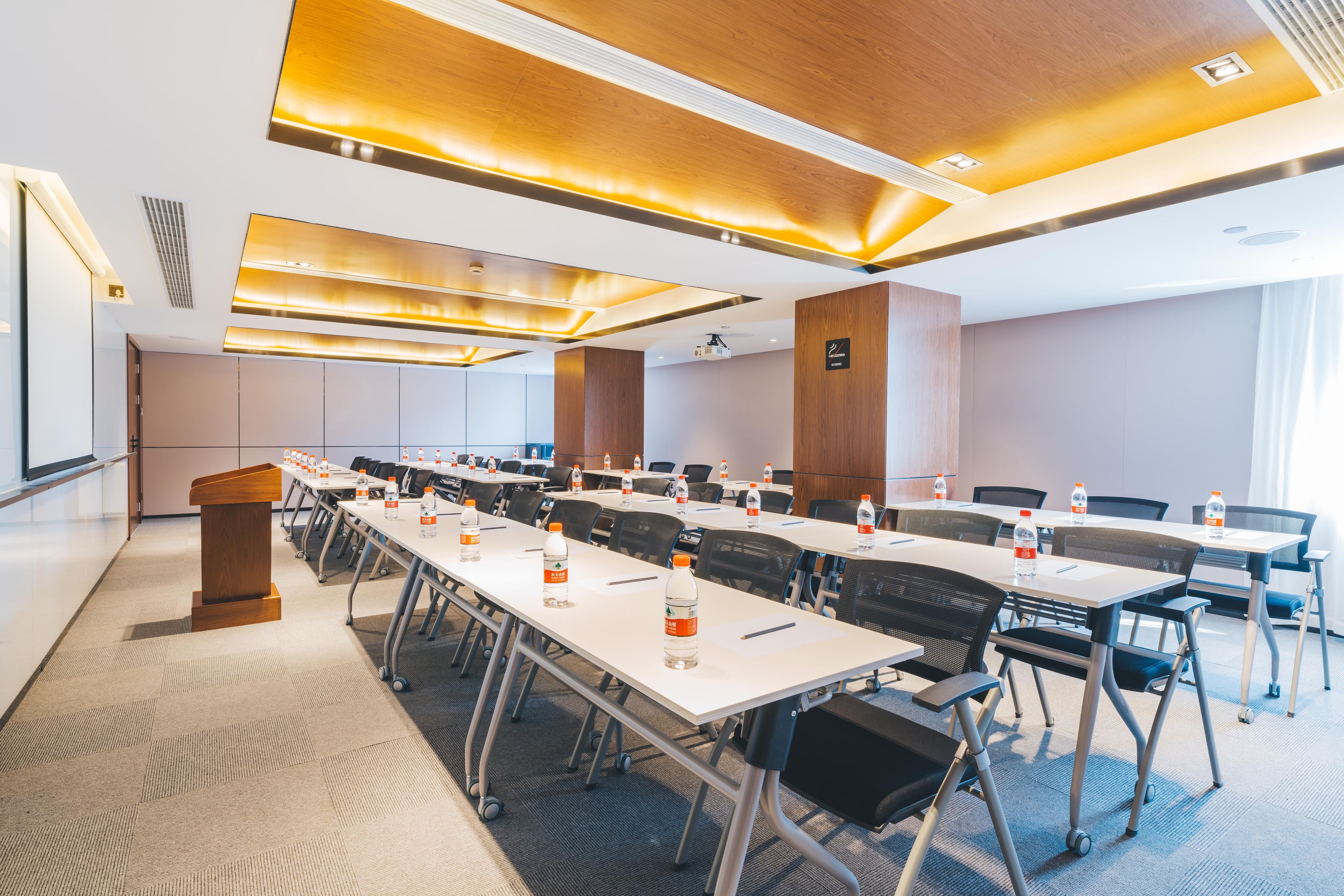 A conference room with multiple tables, chairs, and a podium.