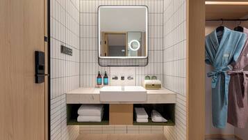 Un baño moderno con un espejo grande, un lavamanos y un perchero para toallas.