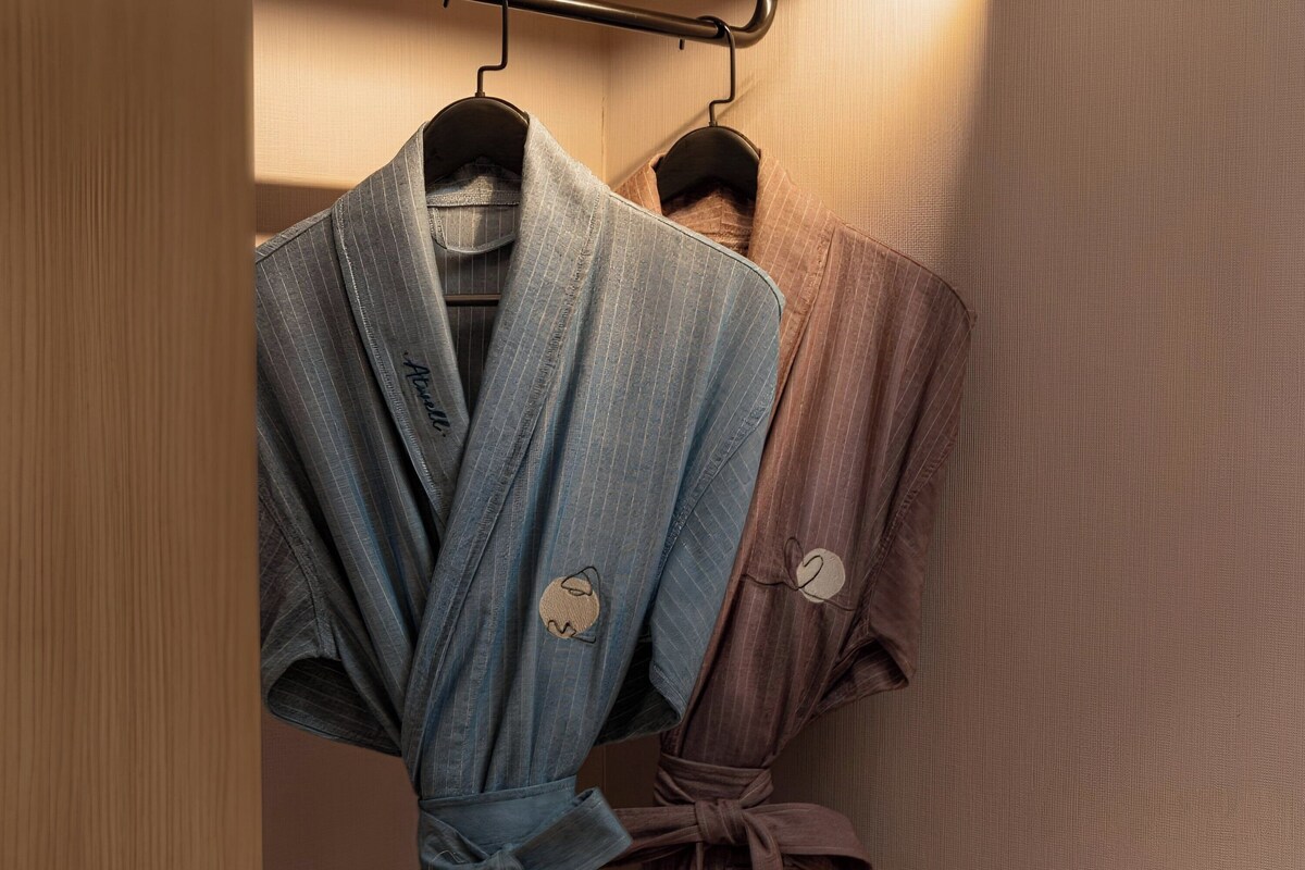 Two bathrobes hanging on a rack in a bathroom.