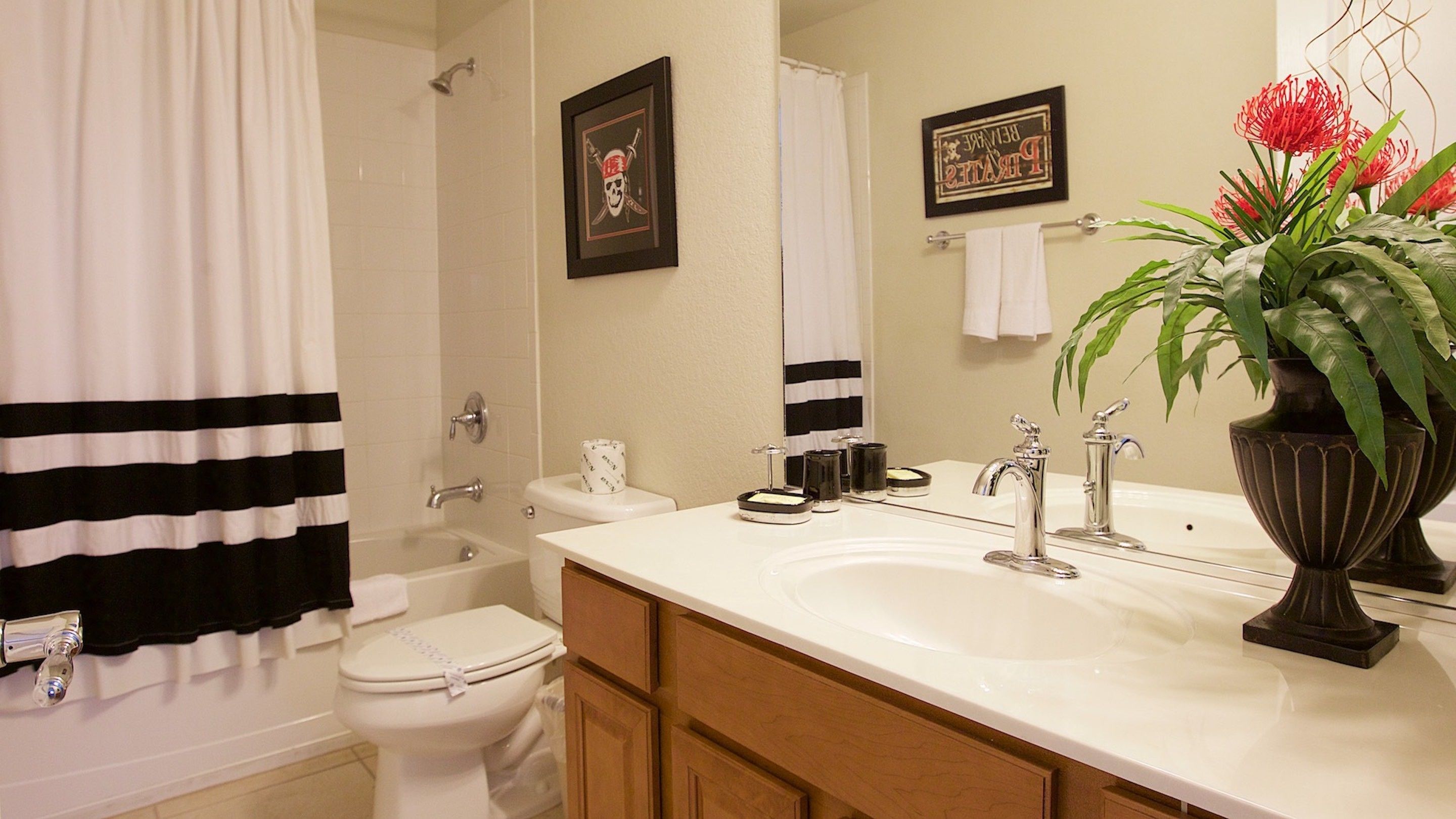 A bathroom with a bathtub, toilet, and sink. There are towels and a potted plant on the counter.