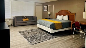 Habitación de hotel con cama, sofá, escritorio y silla.