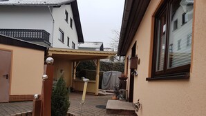 Ein Innenhof mit überdachter Sitzgruppe, einem kleinen Baum und einem Zierzaun.