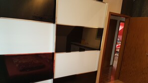 Ein Zimmer mit einer verschiebbaren Trennwand, einer Holztür und einem roten Teppich mit Muster.