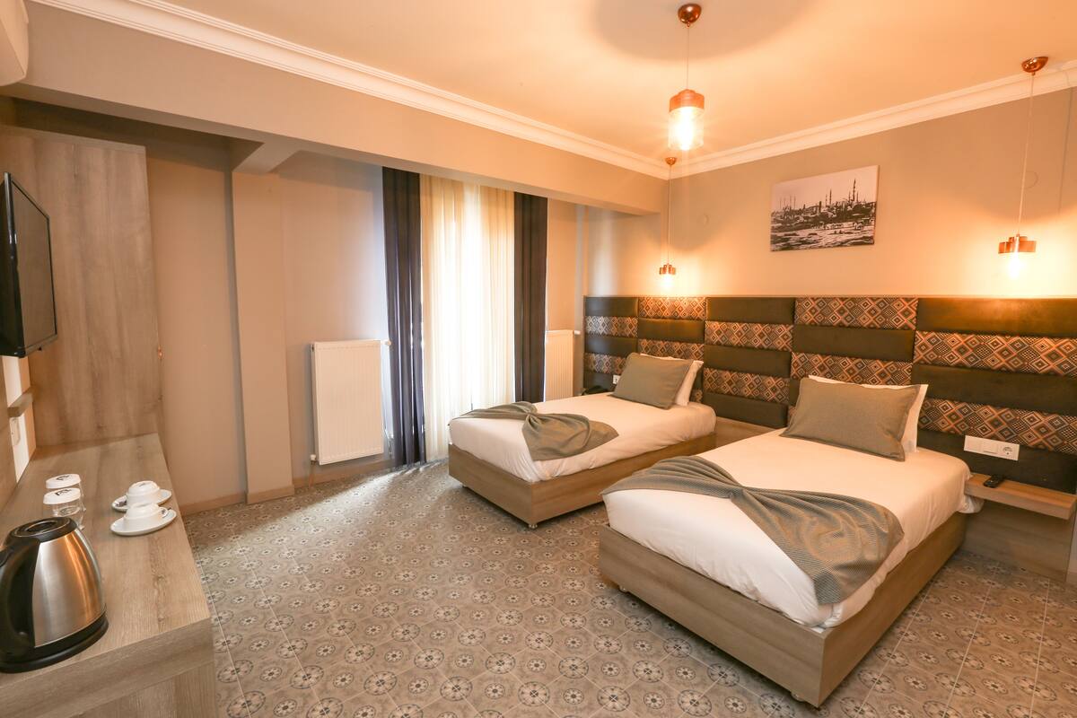 Quarto de hotel com duas camas, televisão de tela plana, cafeteira e radiador.