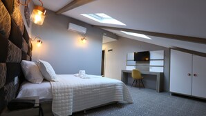 Un dormitorio con cama, mesita de noche, lámpara y escritorio con silla.