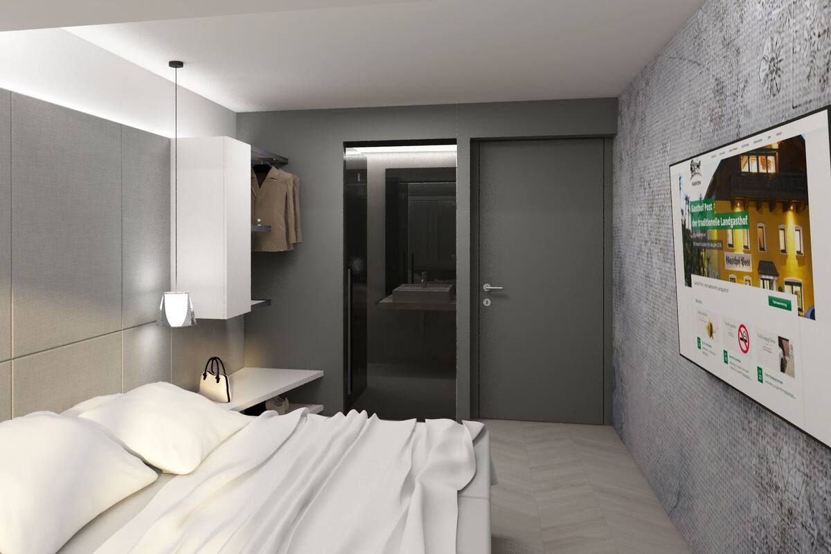 A modern hotel room with a bed, bedside table, and a wall-mounted TV.