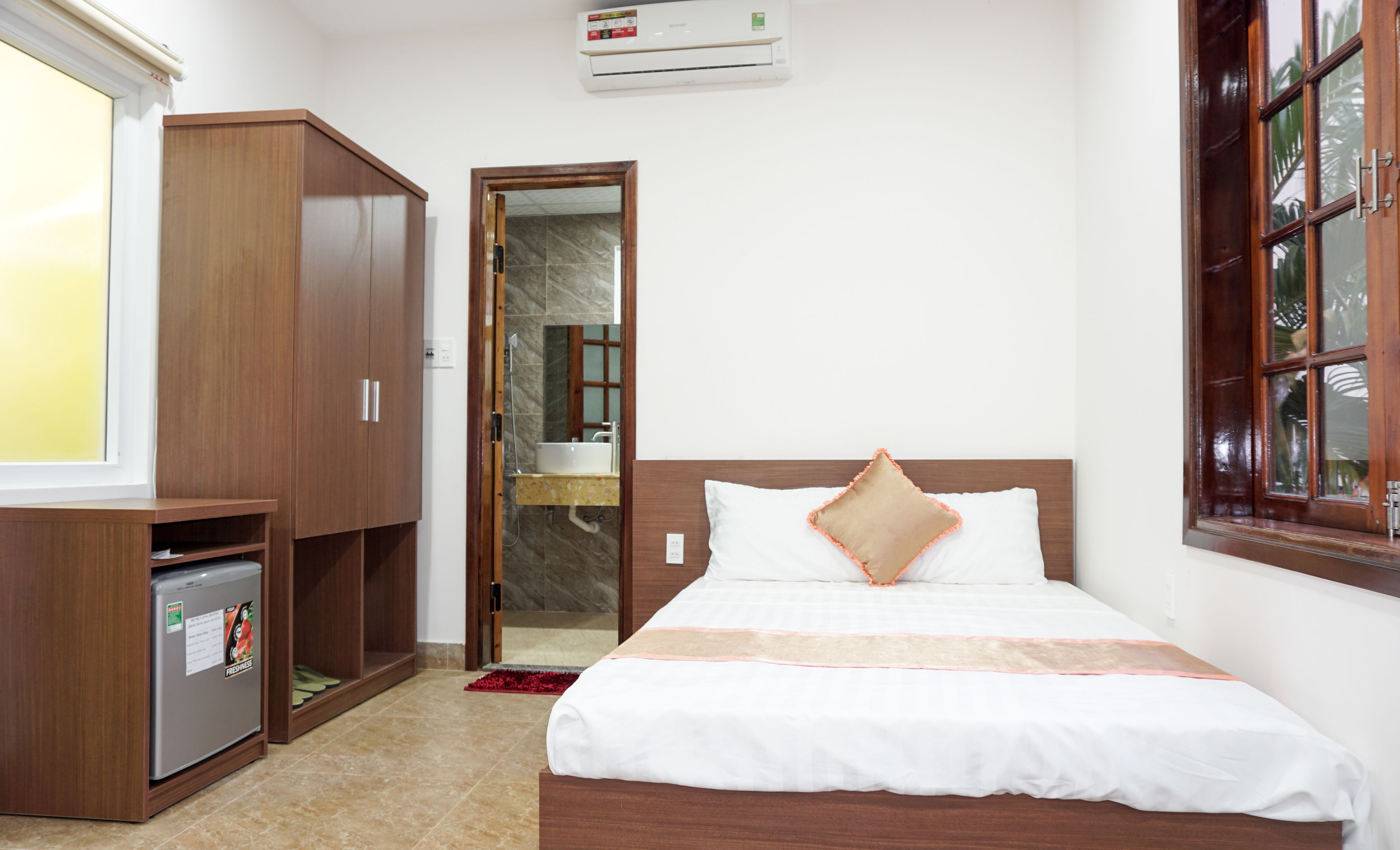 A hotel room with a bed, wardrobe, and a small refrigerator.