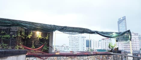Una terraza en la azotea con pared de piedra, una hamaca y plantas colgantes.