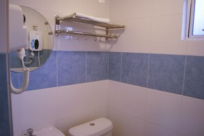 Ein Badezimmer mit Toilette, Handtuchhalter und einem Händetrockner.