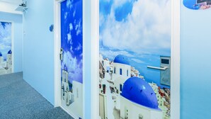 A hallway with blue walls and doors featuring a painted view of a coastal town with white buildings and blue domes. - Santorini Hotel Melaka (Malacca City)