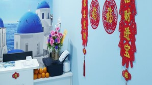 A room with a view of blue-domed buildings, a desk with a computer, a vase with flowers, and red Chinese decorations. - Santorini Hotel Melaka (Malacca City)