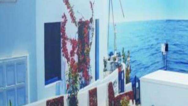 A coastal building with a windmill, a view of the sea, and a person standing by the railing. - Santorini Hotel Melaka (Malacca City)