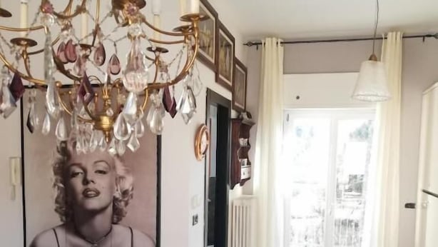 A room with a chandelier, a large framed portrait, checkered flooring, and a view of the outdoors through a door. - Casa con giardino (Turin)