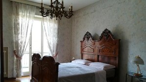 A bedroom with a wooden bed, a chandelier, and a small table with a lamp. - Casa con giardino (Turin)
