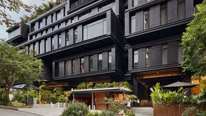 Un edificio de varios pisos con balcones, mobiliario exterior y vegetación.