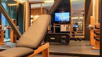 Une salle de sport moderne équipée de matériel d’exercice, d’un téléviseur et d’une grande fenêtre.
