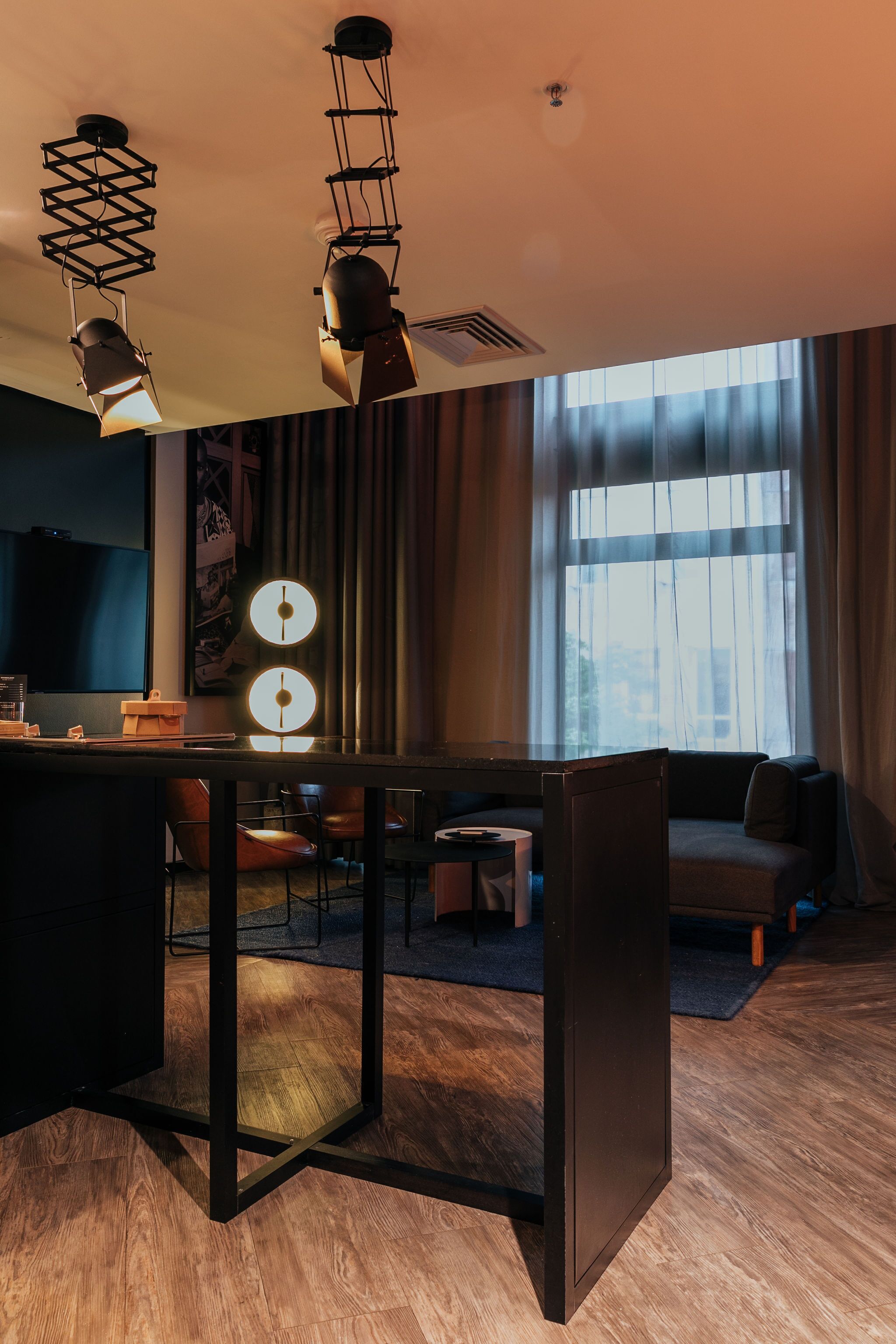 A modern living room with a dining area, a flat-screen TV, and a large window with curtains.