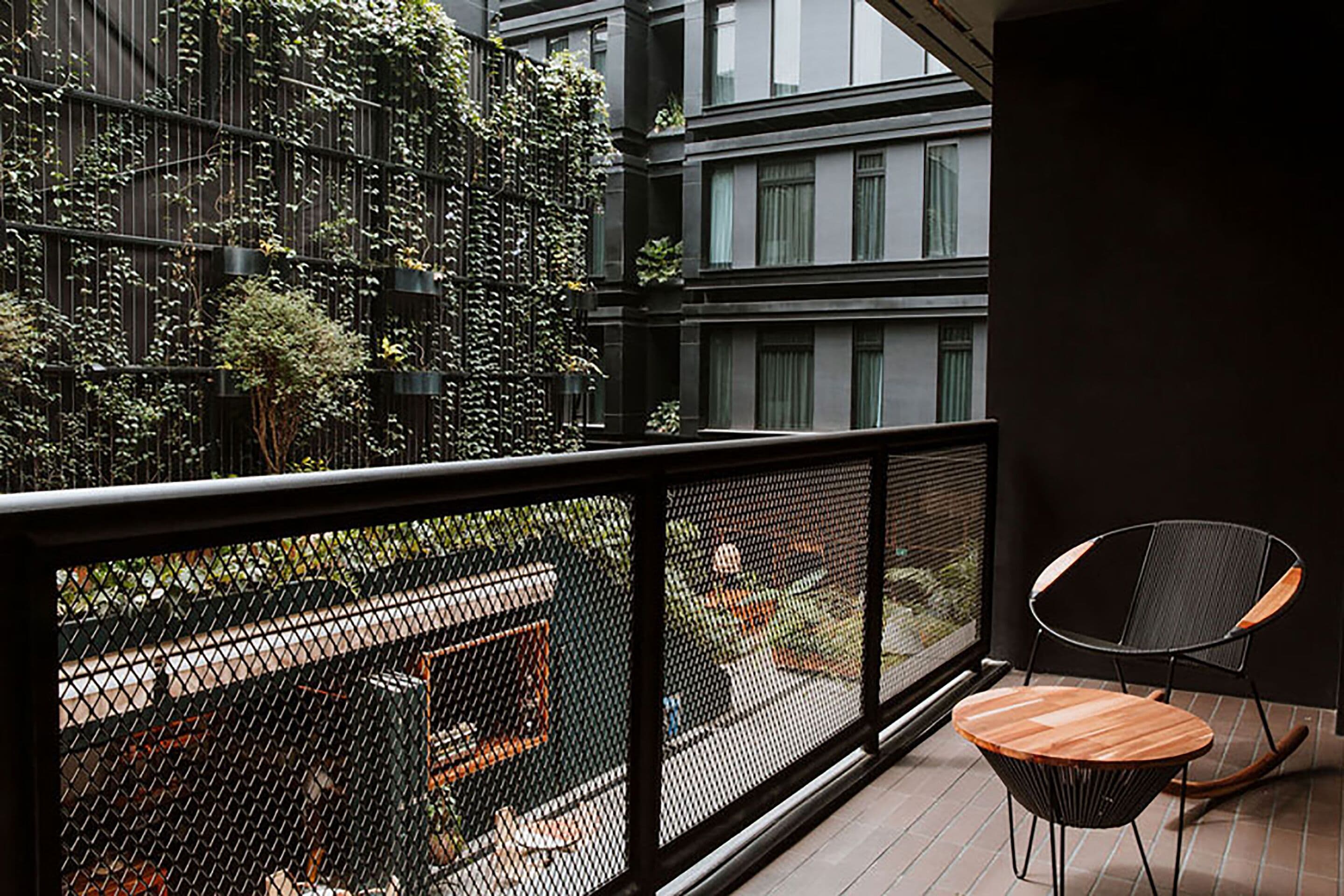 Un balcon doté d’une balustrade en métal noir, d’une table en bois et d’une chaise noire.