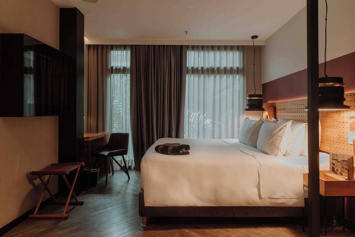 A hotel room with a large bed, a desk, and a chair.