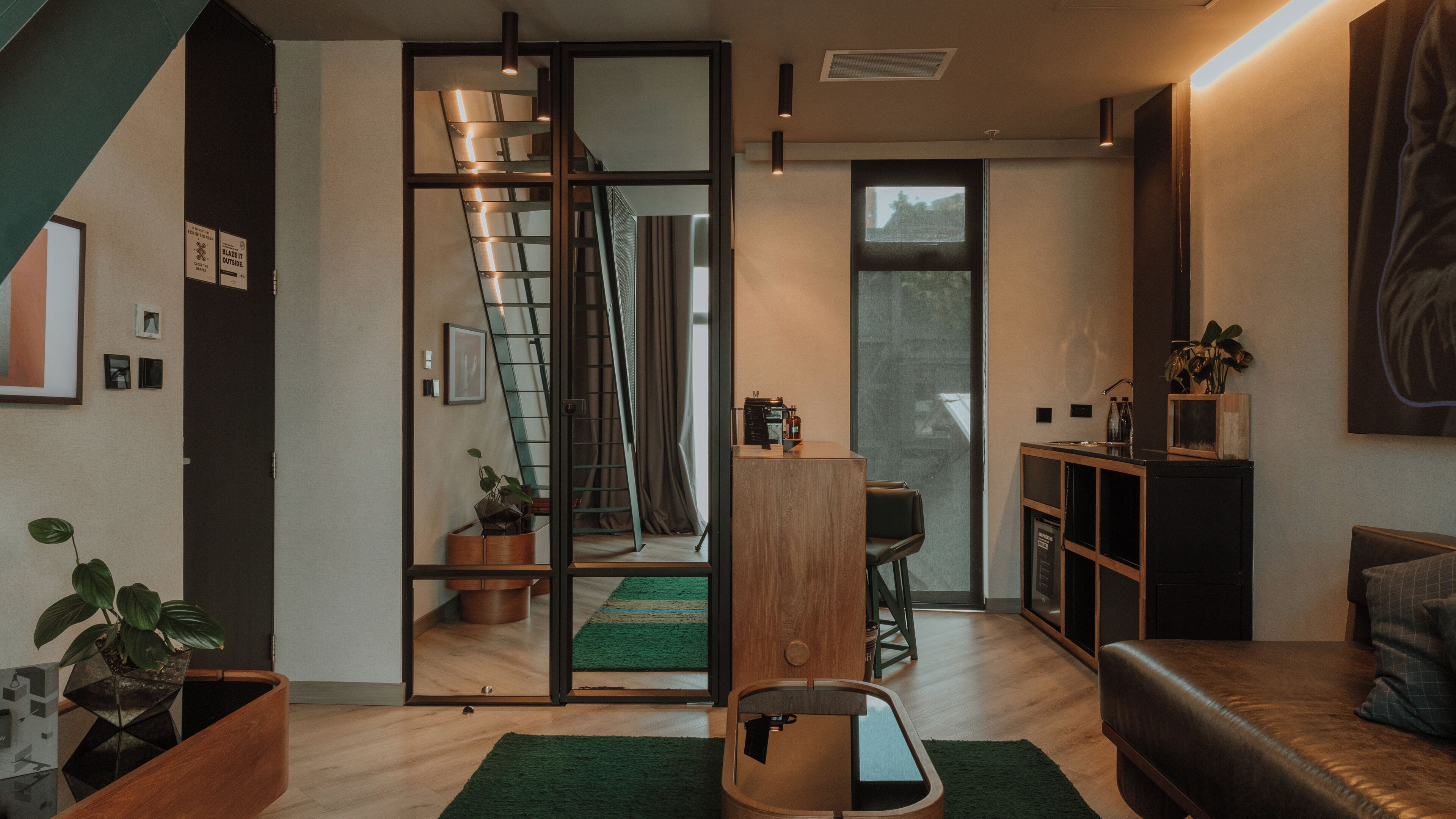 A modern living room with a staircase, a dining area, and a kitchen.