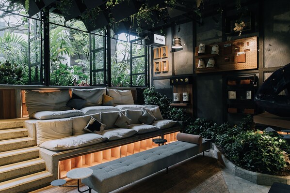 A cozy seating area with a sofa and bench, surrounded by greenery and a pegboard wall with various items. - The Click Clack Hotel Medellin (Medellín)