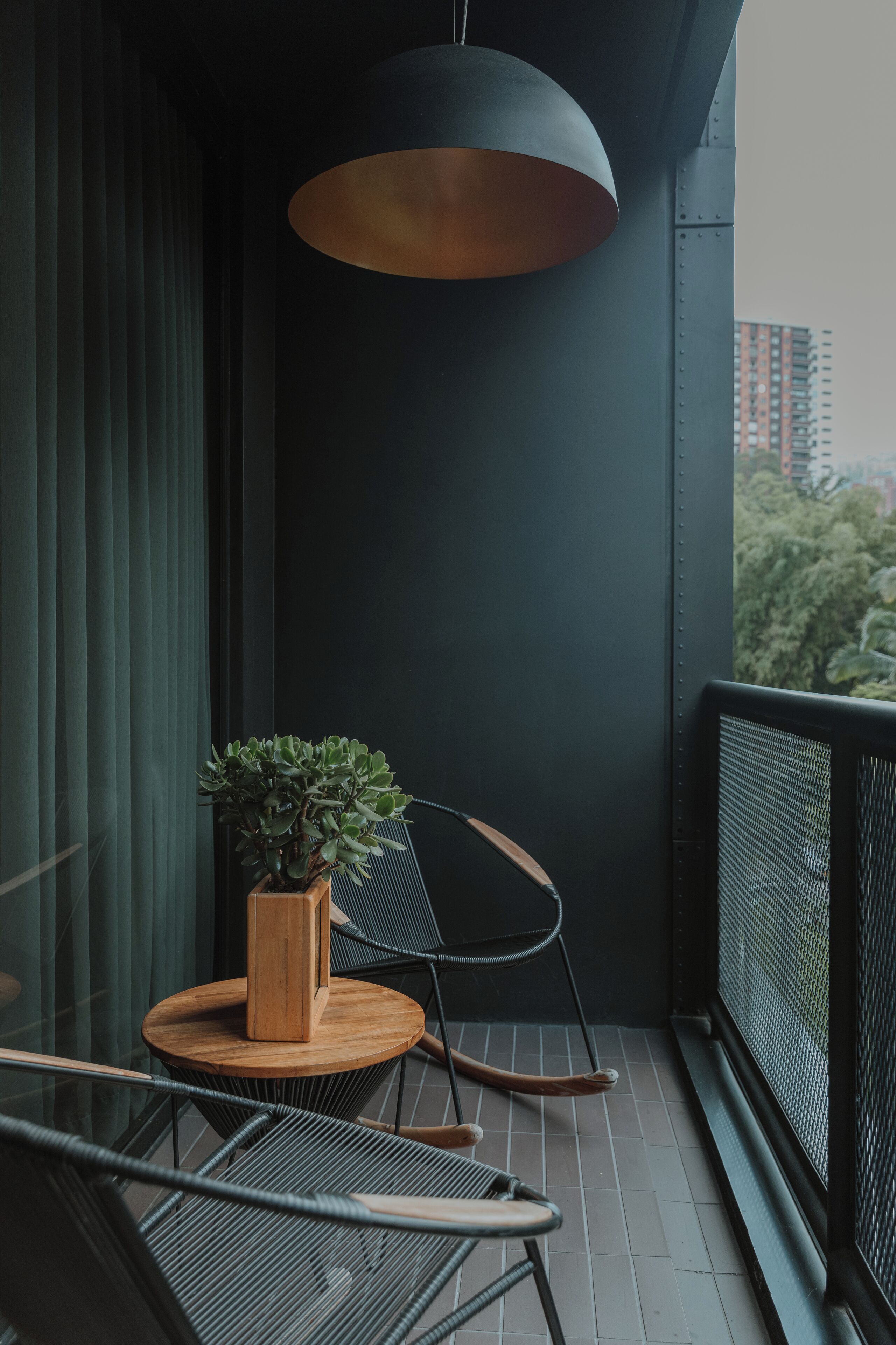 Un balcón con una planta en maceta, una silla y una lámpara colgante.