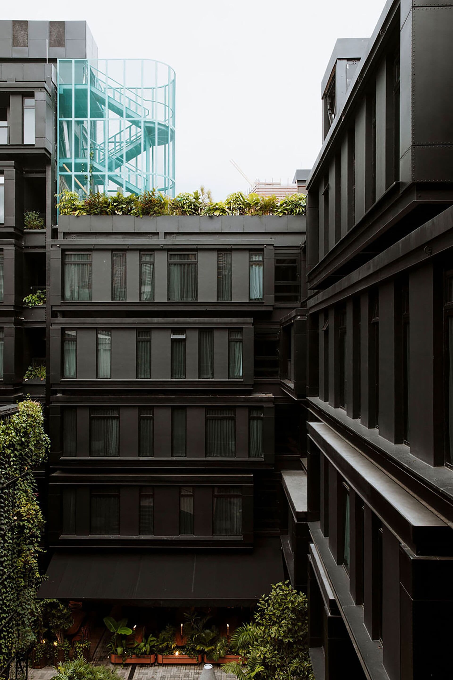 A multi-story building with a modern design, featuring balconies and a glass staircase.