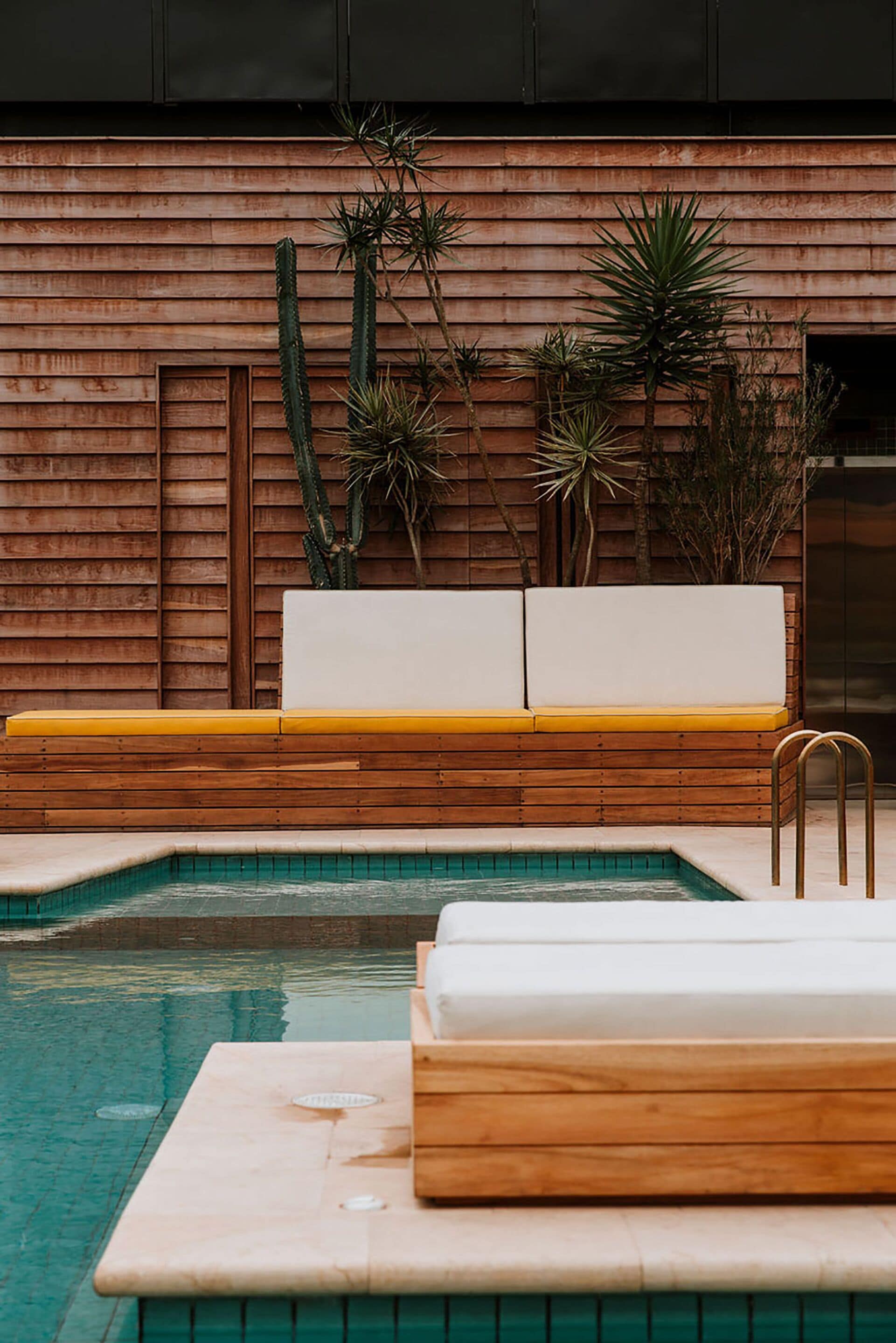Una zona de piscina con bancos de madera y una escalera.