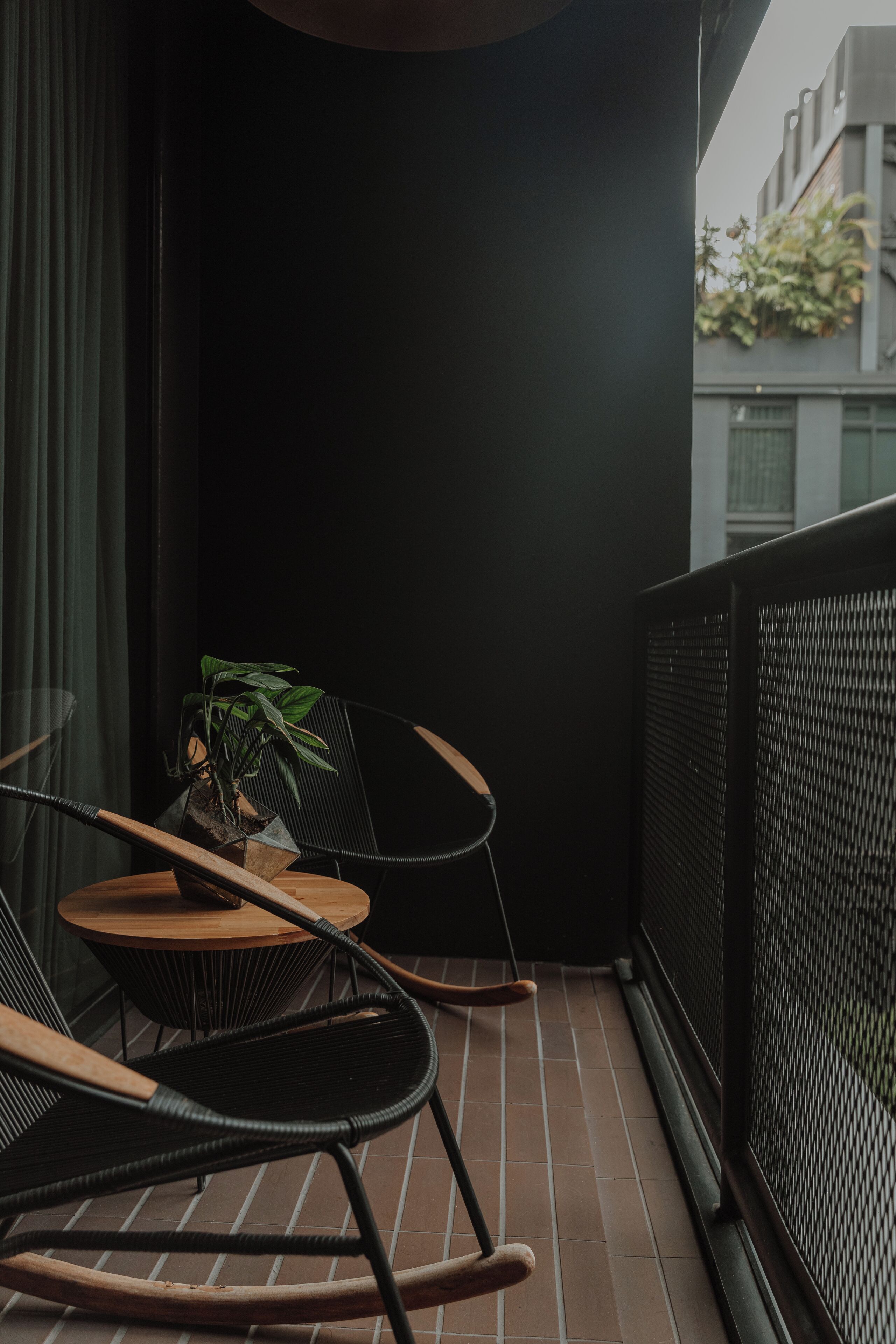 A balcony with a black chair, a small round table, and a potted plant.