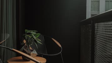 A balcony with a black chair, a small round table, and a potted plant.