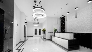 Un moderno vestíbulo de hotel con una recepción, decoración en blanco y negro y un diseño geométrico en la pared.