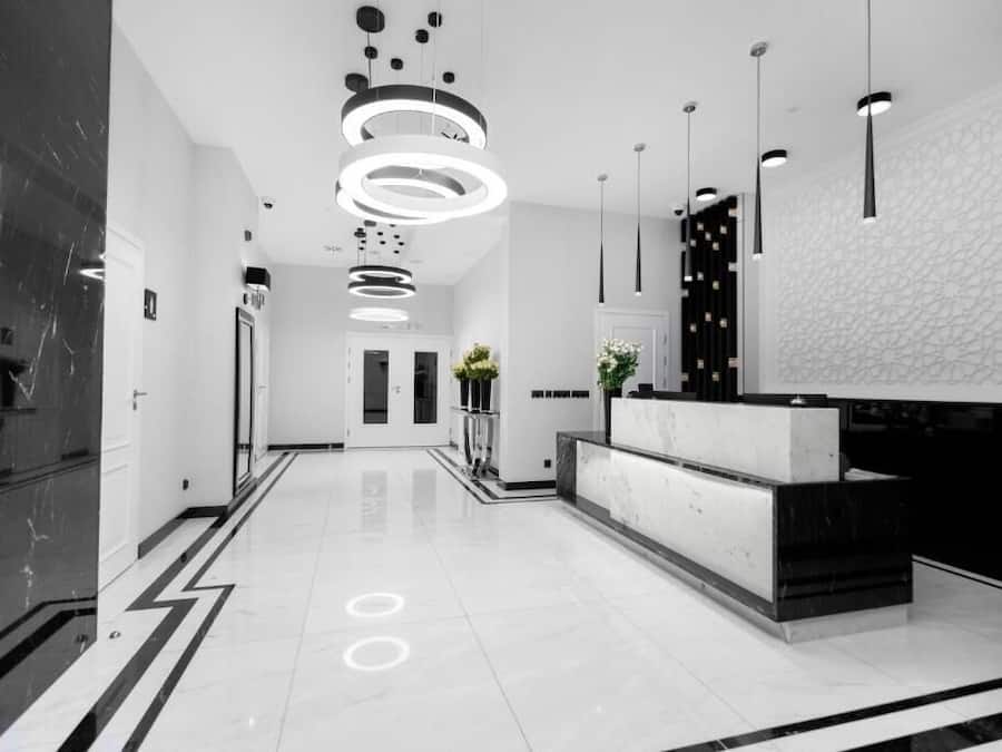 A modern hotel lobby with a reception desk, black and white decor, and a geometric wall pattern.