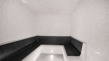 Bathroom features a geometric design with white tiles and a black-tiled bench.
