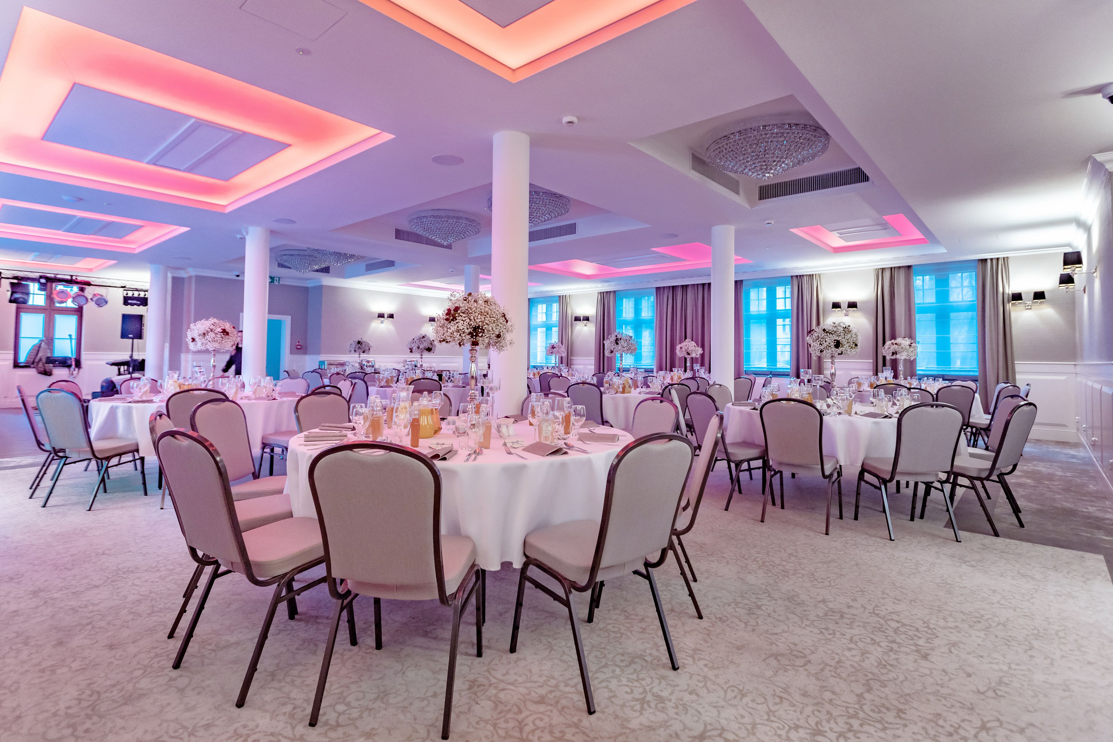 Una gran sala de banquetes amb taules rodones, cadirees i centrals florals.