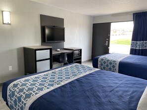 A hotel room with two beds, a desk with a television, a refrigerator, and a window with curtains. - Executive Inn (Mount Pleasant)