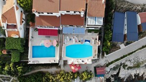 An aerial view of a resort with two swimming pools, a beach area, and a rocky coastline. - Apartments Villa Marija (Seget)