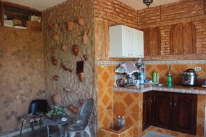 Eine Küche mit Steinwänden, Holzschränken und einem Essbereich mit Tisch und Stühlen.