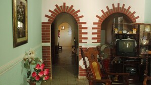 A living room with brick arches, a television, and a fan. - Hostal Rio De Agua Vivo (Trinidad)