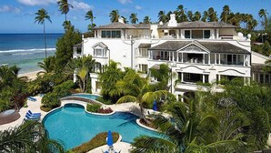Un grand bâtiment blanc doté d’une piscine, entouré de palmiers et offrant une vue sur la plage.
