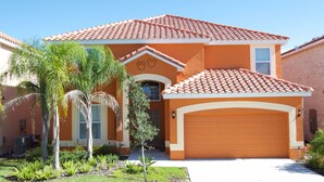 A two-story house with a red-tiled roof, a garage, and a front yard with palm trees. - Stirling Vacation Home at Solterra (Davenport)