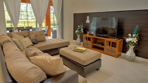A modern living room with a sectional sofa, a flat-screen TV on a wooden stand, and two decorative vases. - Stirling Vacation Home at Solterra (Davenport)