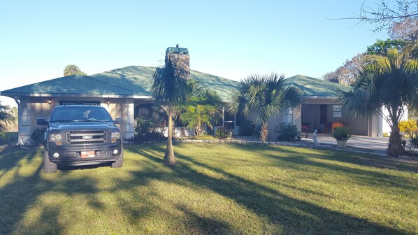 A house with a driveway, a lawn, and a parked truck. - Beautiful Vacation Home CBC FARMS (Okeechobee)