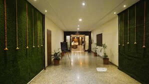 Eine Hotelhalle mit grüner Wandstruktur, Blumentöpfen und einer Rezeption.