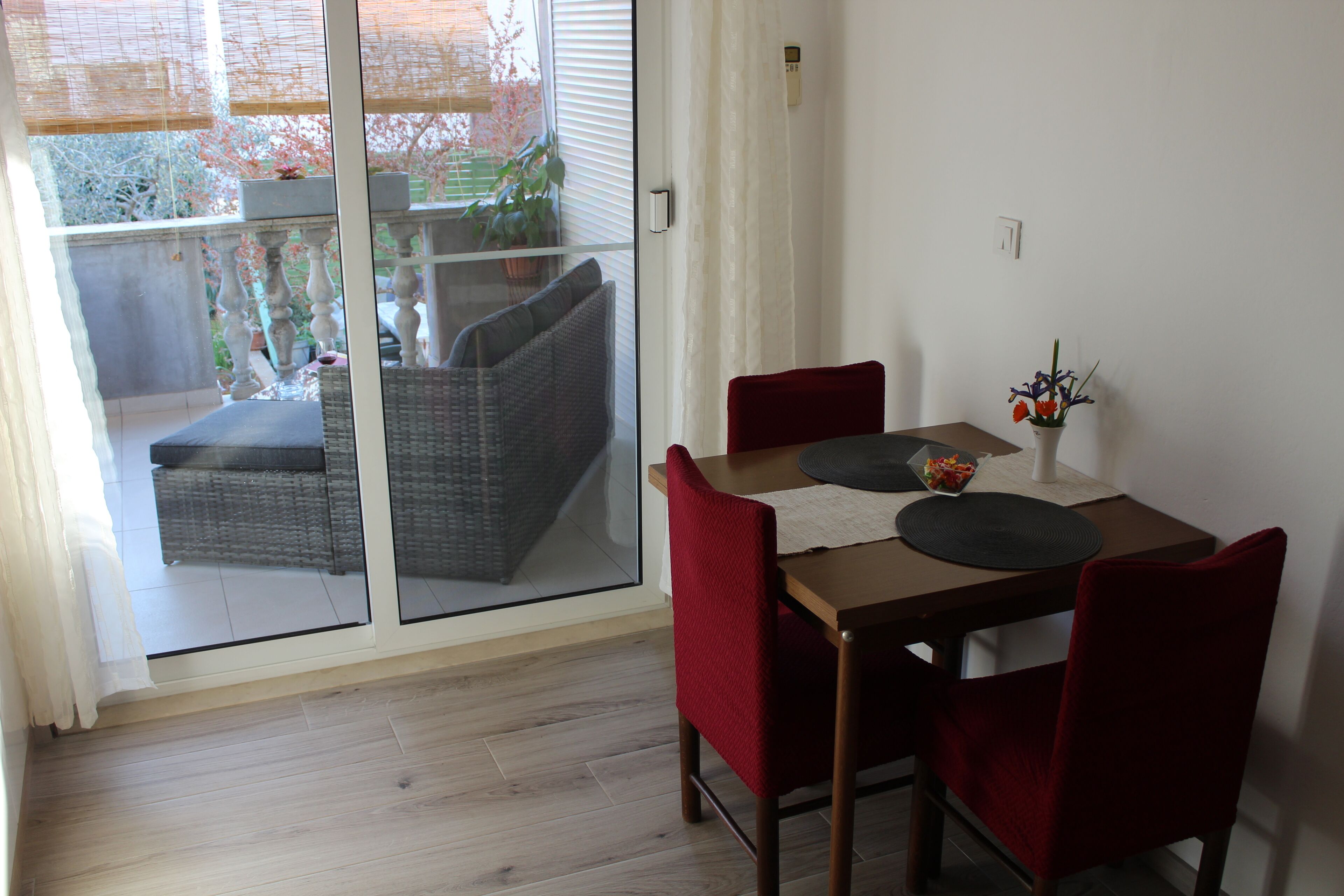 A dining area with a table, chairs, and a view through a glass door to an outdoor balcony.